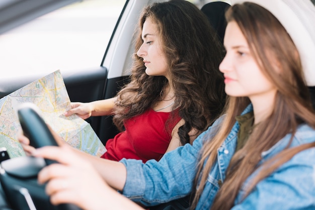 Mujer que mira el mapa mientras que monta el coche