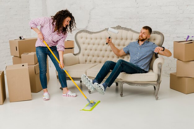 Mujer que moja el piso cerca del hombre de reclinación