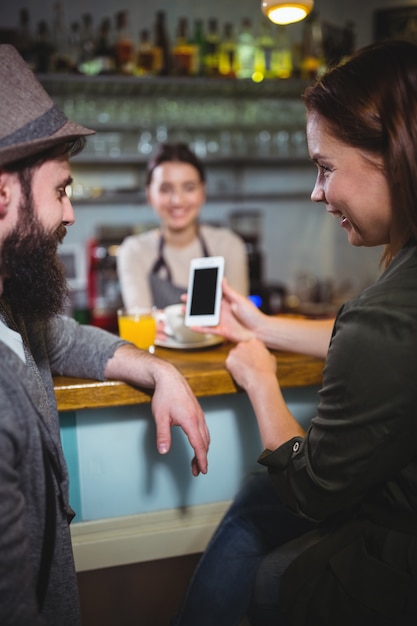 Foto gratuita mujer que muestra el teléfono móvil para el hombre