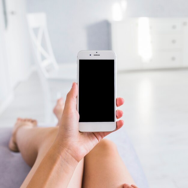 Una mujer que muestra el teléfono móvil con pantalla en blanco