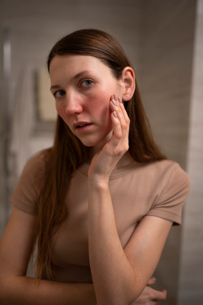 Mujer que se ocupa de la condición de la piel de la rosácea en la cara