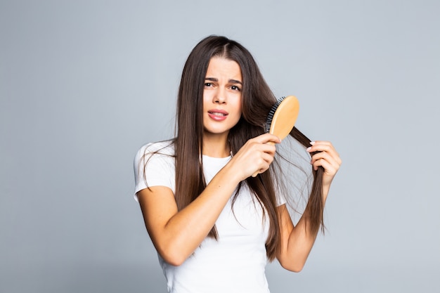 Mujer que se peina el pelo aislado en un blanco