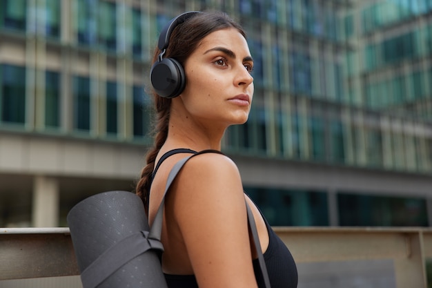 mujer que va a practicar yoga al aire libre va al estudio de gimnasia hace deporte sola en el centro durante la cuarentena regresa a la actividad física después de que se autoaisla escucha música popular