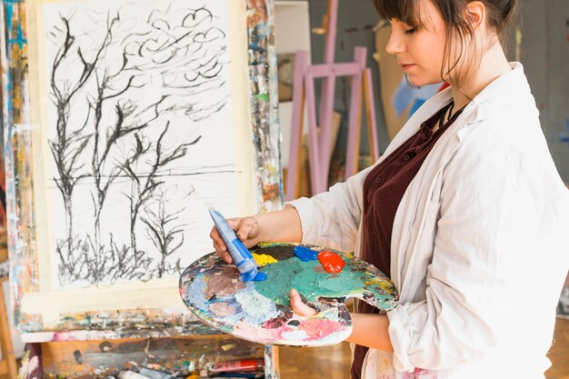 Mujer que prepara la paleta de colores para pintar en el taller