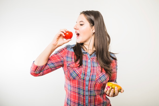 Mujer que pretende morder el tomate