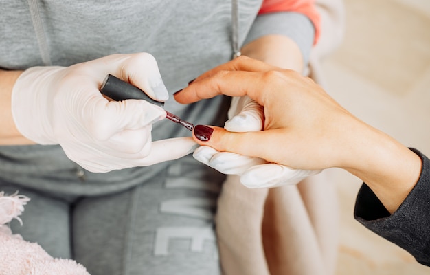 Foto gratuita una mujer que recibe manicura de una mujer con guantes y máscara en el salón de belleza durante el día