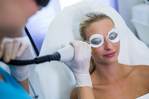 Mujer que recibe tratamiento de depilación láser en la cara