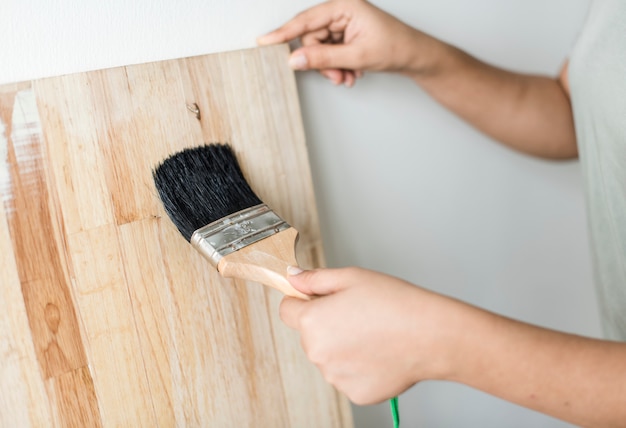 Foto gratuita mujer que recubre una plancha de madera con laca.