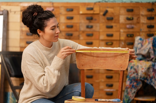 Foto gratuita mujer que restaura la vista lateral de la silla de madera