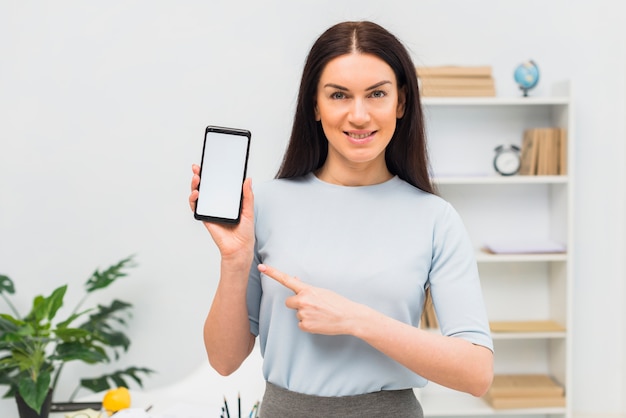 Mujer que señala el dedo en el teléfono inteligente con pantalla en blanco