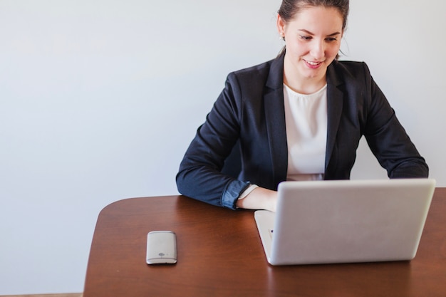 Foto gratuita mujer que se sienta en el escritorio que trabaja en la computadora portátil