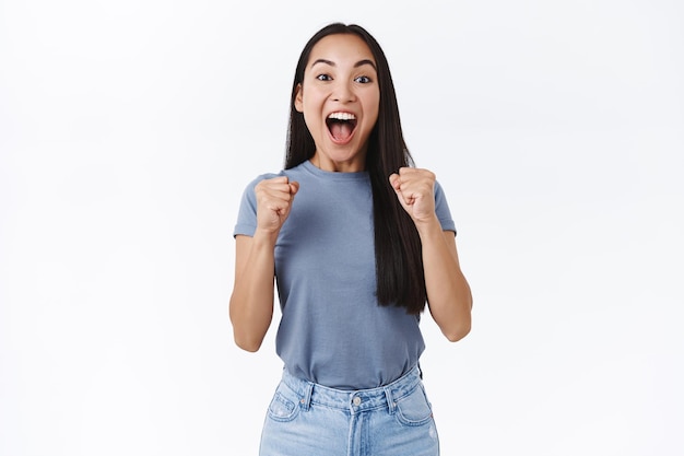 Mujer que siente dulce éxito, grita de felicidad y alegría, aprieta los puños saltando como triunfante