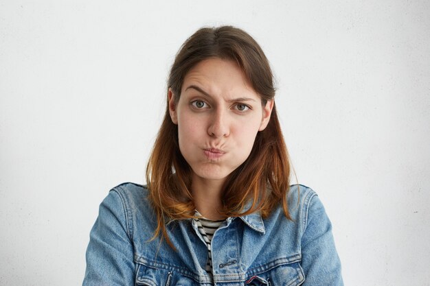 Mujer que sopla sus mejillas está molesta levantando las cejas