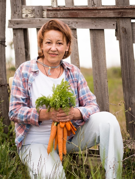 Foto gratuita mujer que sostiene algunas zanahorias en su mano