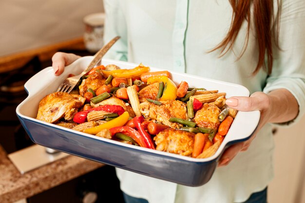 Mujer que sostiene la bandeja de comida para la cena