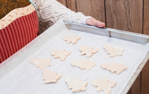 Mujer que sostiene una bandeja para hornear con galletas de Navidad