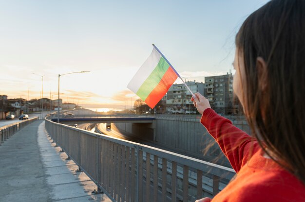 Mujer que sostiene la bandera búlgara al aire libre