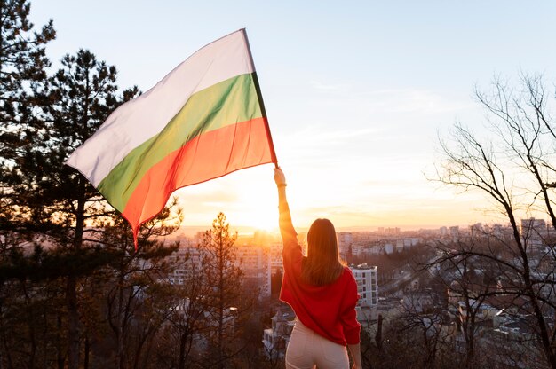 Mujer que sostiene la bandera búlgara al aire libre