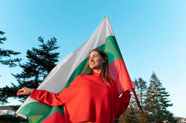 Mujer que sostiene la bandera búlgara al aire libre