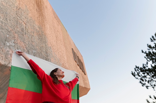 Mujer que sostiene la bandera búlgara al aire libre