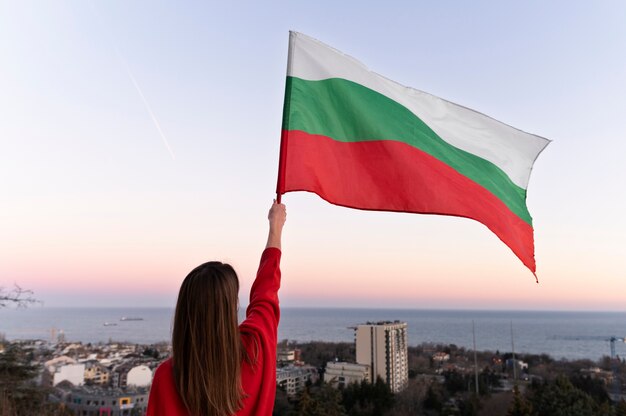 Mujer que sostiene la bandera búlgara al aire libre