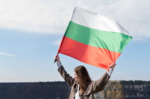 Mujer que sostiene la bandera búlgara al aire libre