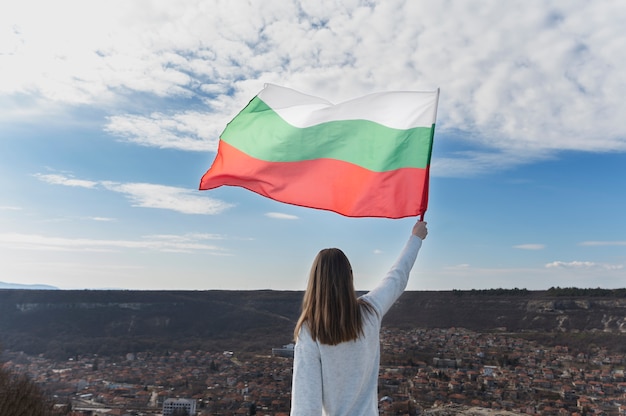 Mujer que sostiene la bandera búlgara al aire libre