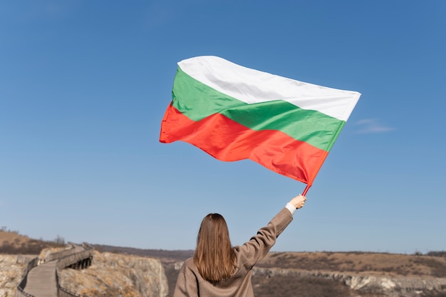 Mujer que sostiene la bandera búlgara al aire libre