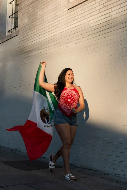 Mujer que sostiene la bandera mexicana en la calle