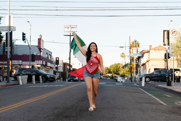 Mujer que sostiene la bandera mexicana en la calle