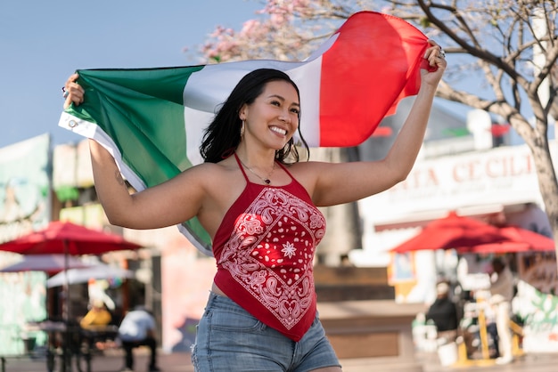 Mujer que sostiene la bandera mexicana en la calle