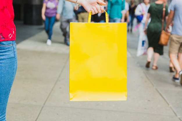 Mujer que sostiene el bolso de compras amarillo