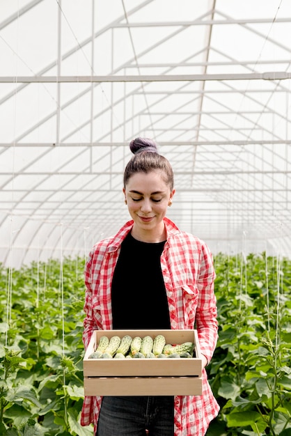 Foto gratuita mujer que sostiene el cubo con pepinos