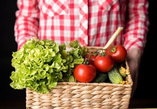 Mujer que sostiene un cubo de verduras