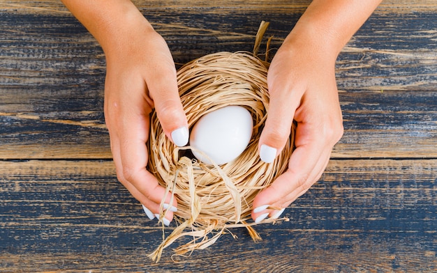 Foto gratuita mujer que sostiene el huevo en el nido de paja