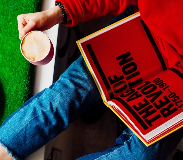 Foto gratuita mujer que sostiene el libro y la taza de café