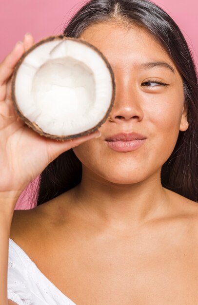 Mujer que sostiene la mitad de la fruta de coco