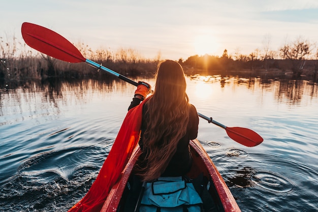 Mujer que sostiene la paleta en un kayak en el río
