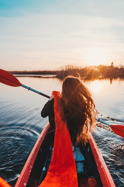 Mujer que sostiene la paleta en un kayak en el río