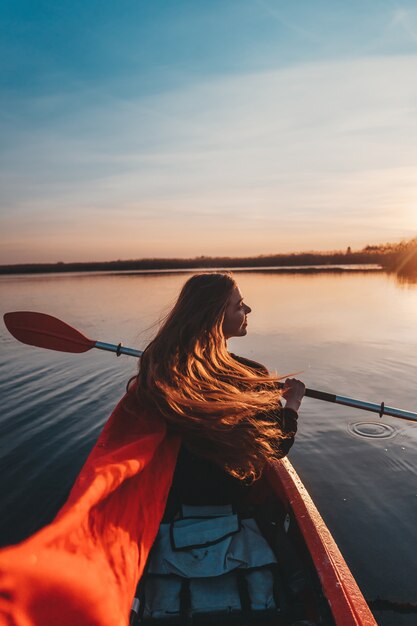 Mujer que sostiene la paleta en un kayak en el río