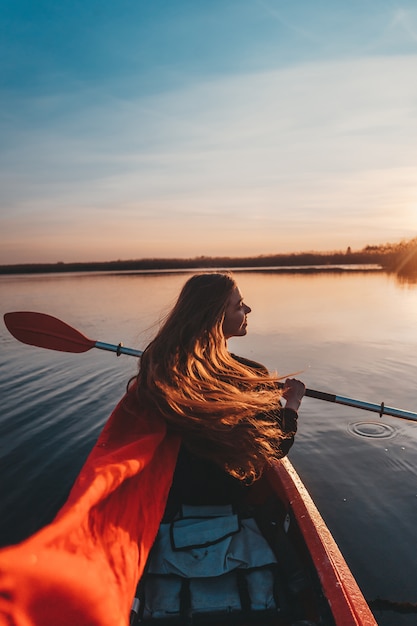 Mujer que sostiene la paleta en un kayak en el río