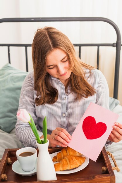 Mujer que sostiene la tarjeta de felicitación con el dibujo del corazón