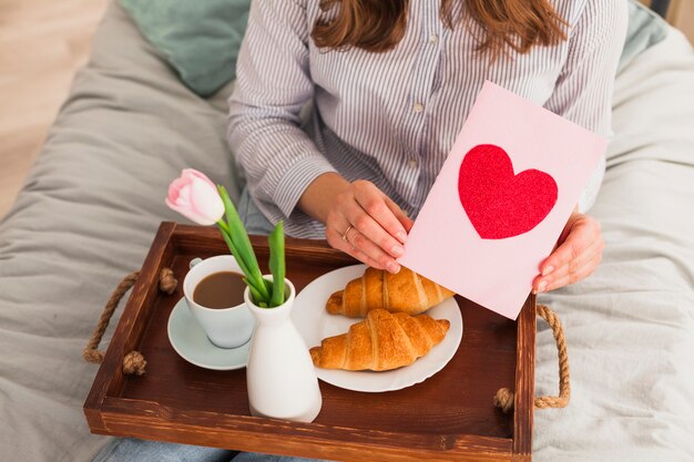 Mujer que sostiene la tarjeta de felicitación con el dibujo rojo del corazón