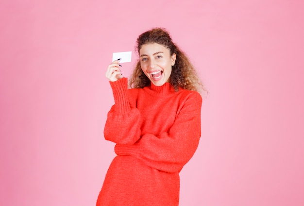 mujer que sostiene una tarjeta de presentación se ve muy feliz y sorprendida.