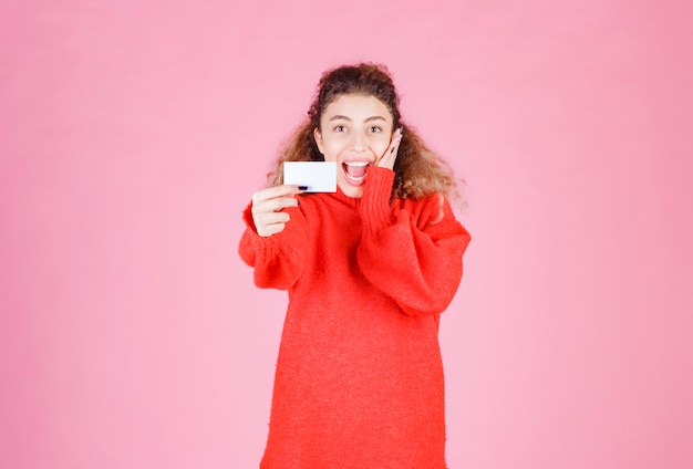 mujer que sostiene una tarjeta de presentación se ve muy feliz y sorprendida.