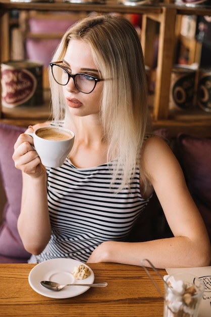 Mujer que sostiene la taza de café en el café