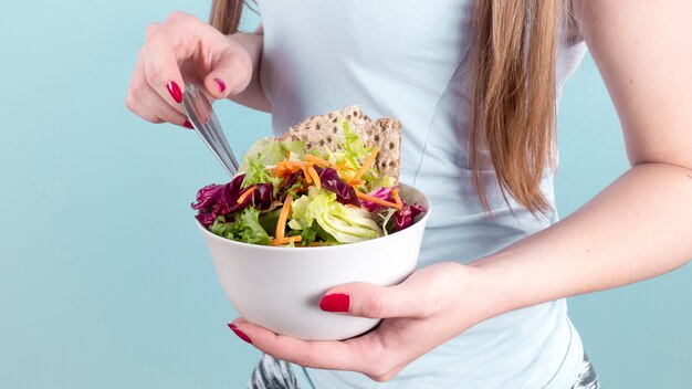 Mujer que sostiene un tazón grande con ensalada de verduras