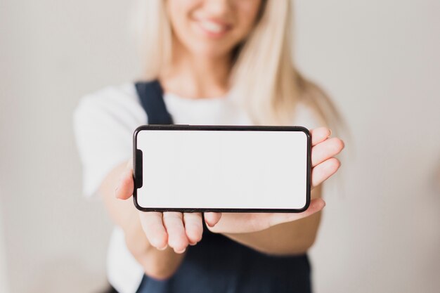 Mujer que sostiene el teléfono inteligente con maqueta