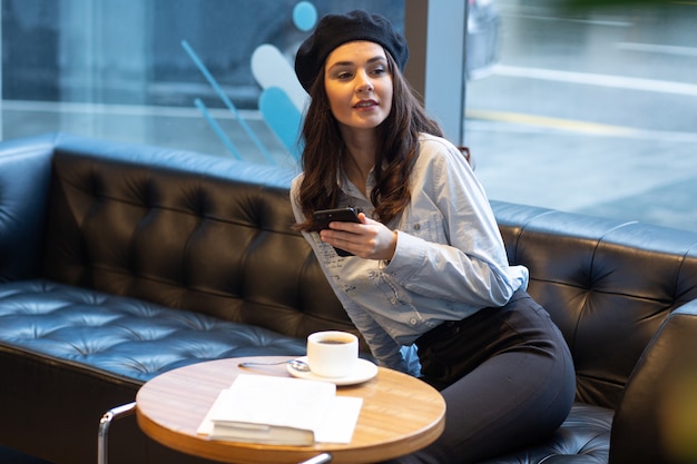 Foto gratuita mujer que sostiene el teléfono inteligente en sus manos