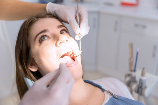 Mujer que tiene dientes examinados en dentistas